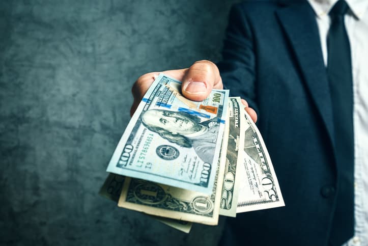 A person extends paper cash by hand