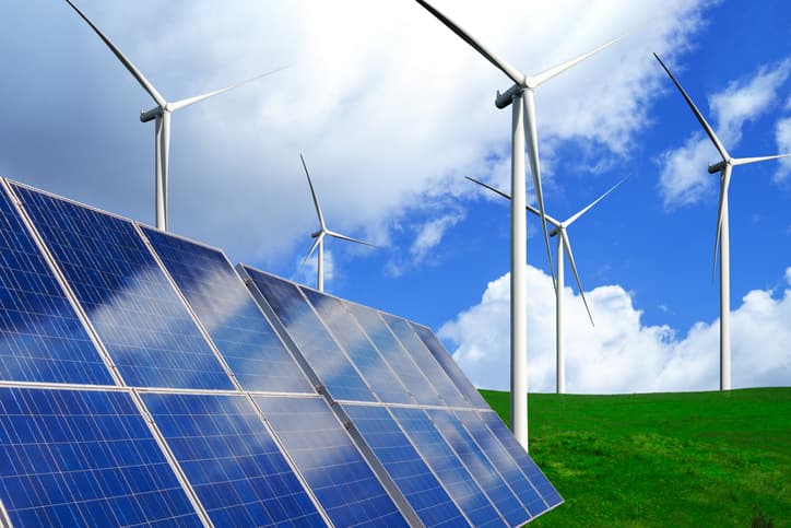 Solar panels next to wind turbines in a field