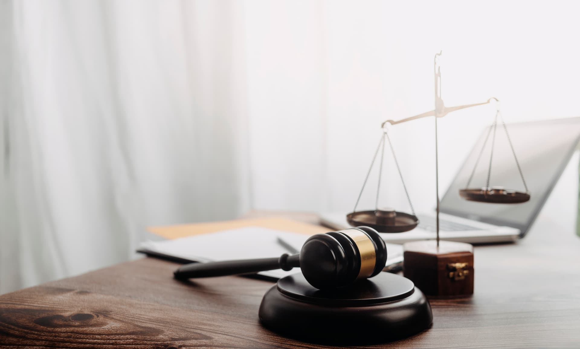 Image of a gavel and block and a scale on a desk.