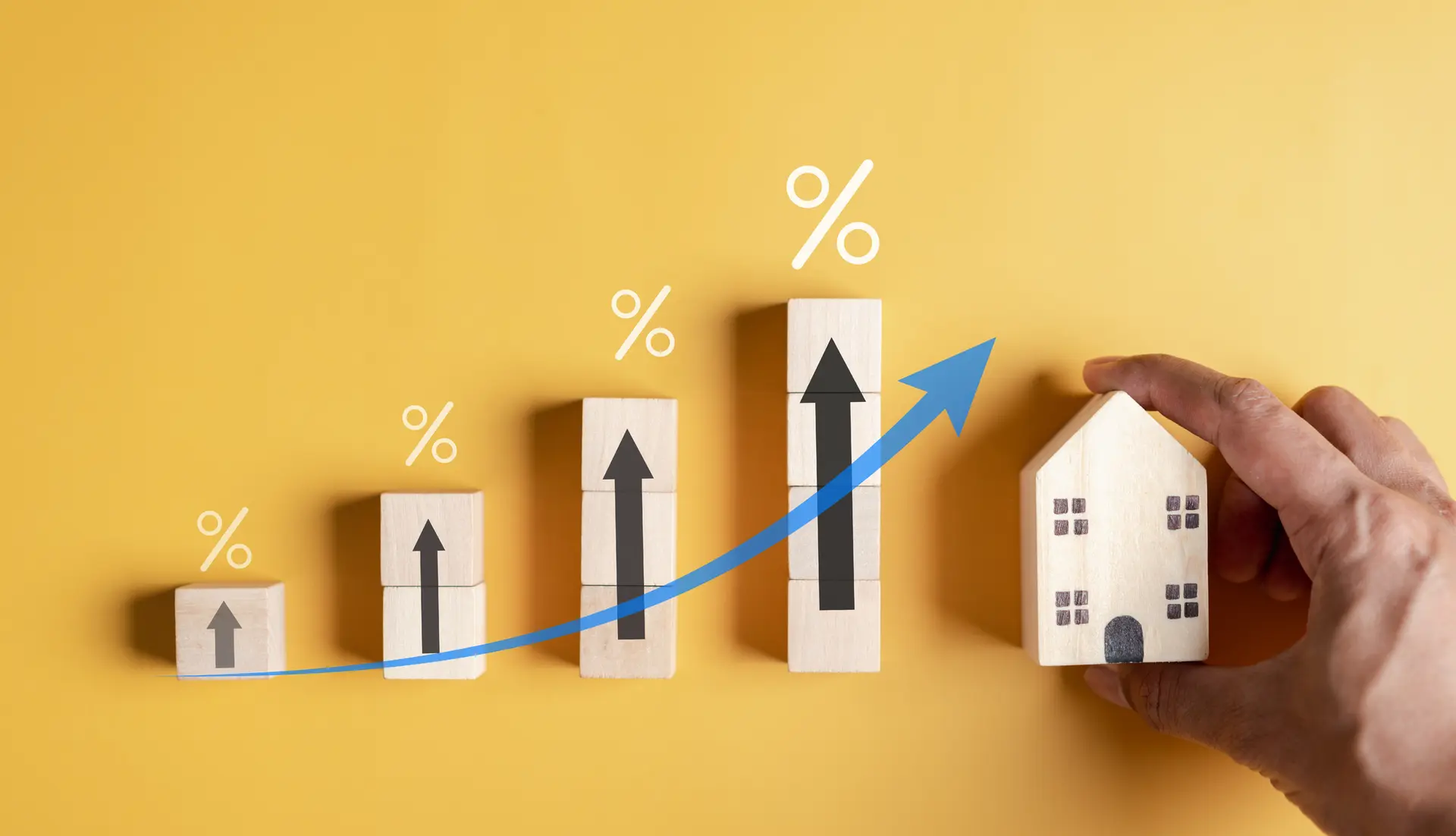 Increasing chart made of wood next to building held in hand on yellow background
