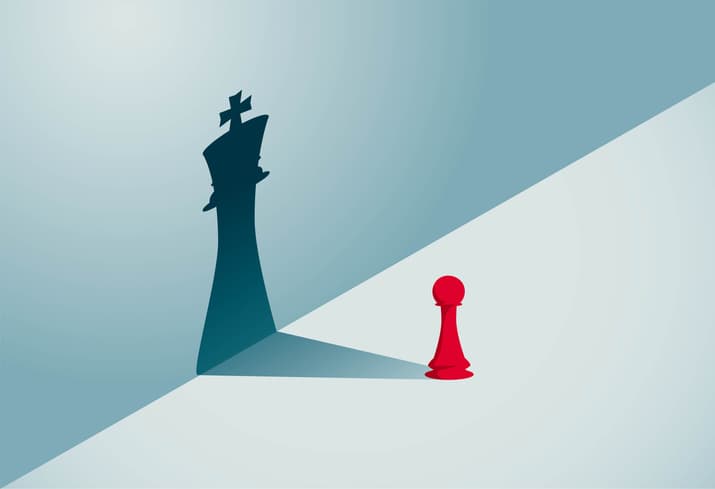 A red pawn chess piece with a shadow of a king chess piece