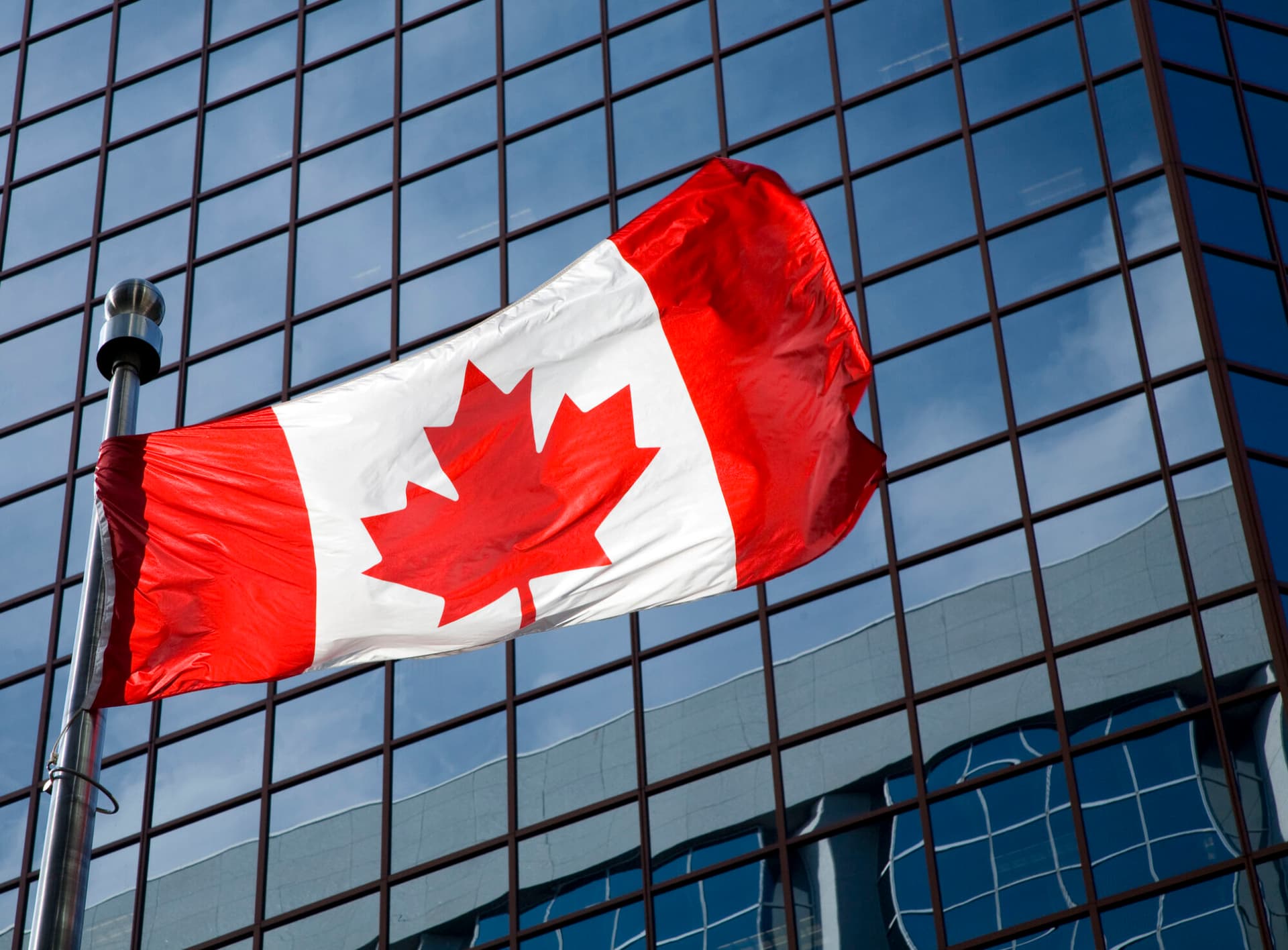 Canadian flag in front of modern building.