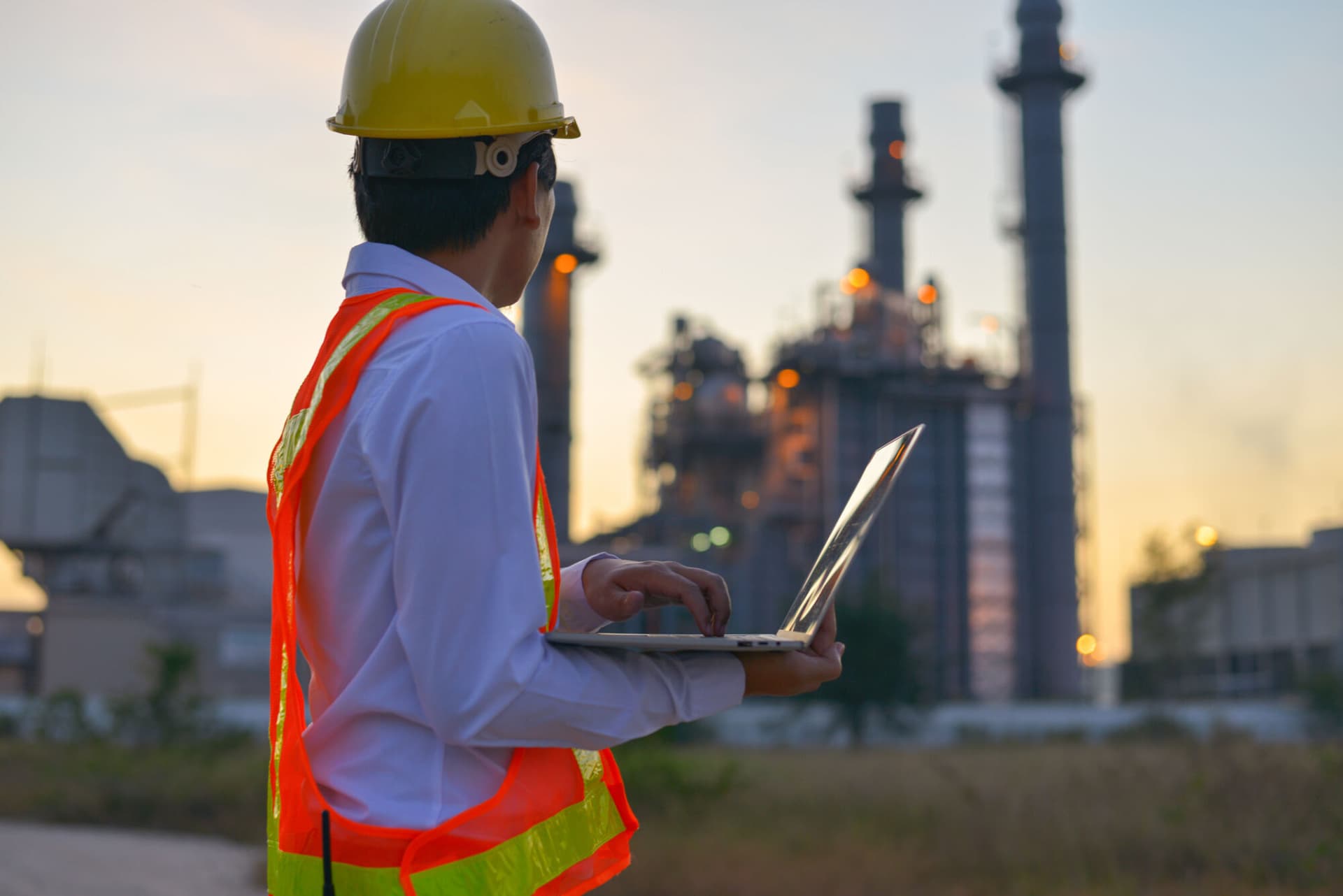 Measuring energy. Young engineers are using a laptop while working at a large factory.