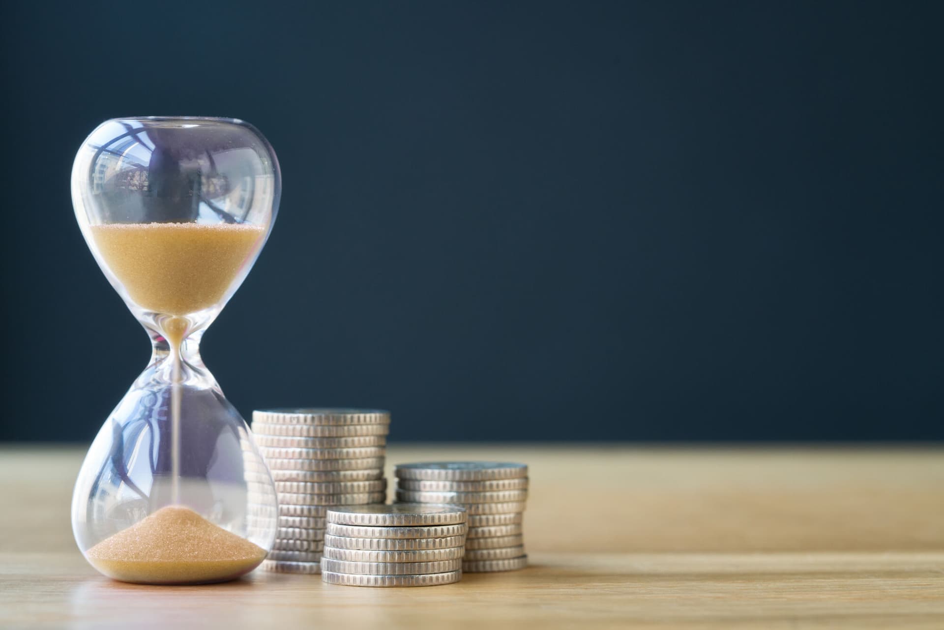 An hourglass next to a stack of coins