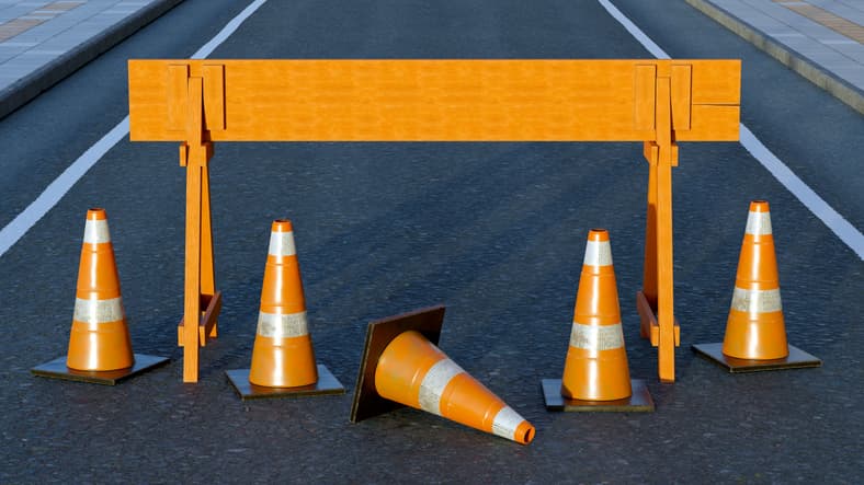 Under construction traffic cones and orange barrier road boundary.