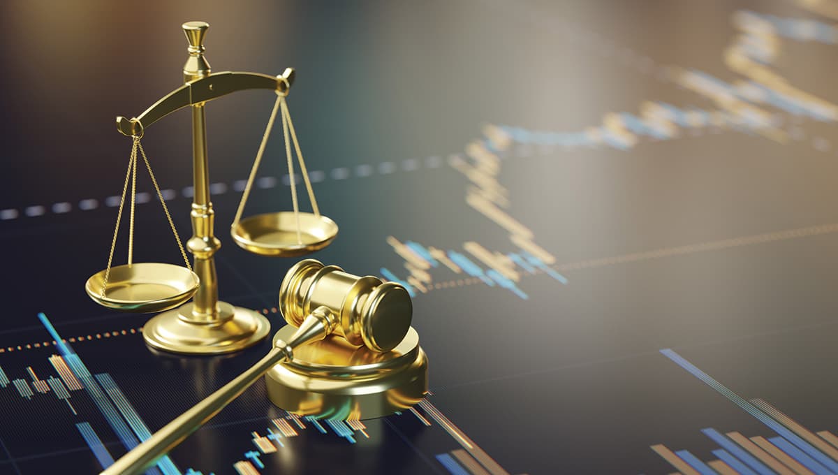A courtroom gavel and golden scales of justice on a financial analysis chart, representing legal and economic themes.