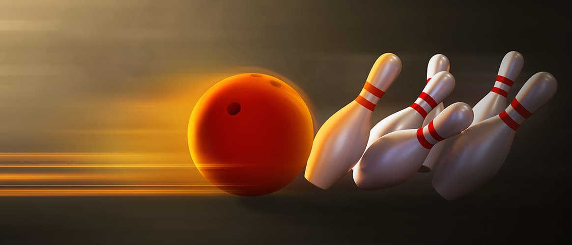 A bowling ball knocks over bowling pins