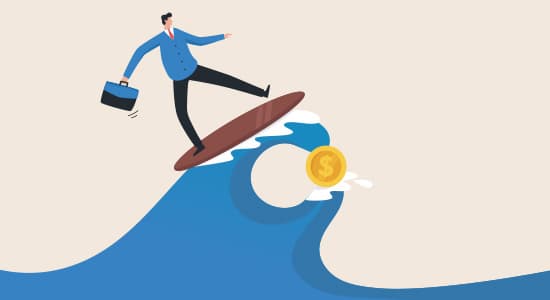 A man stands on a surfboard surfing a wave that has money in it