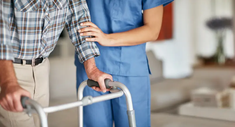 Shot of a woman assisting her elderly patient who's using a walker for support