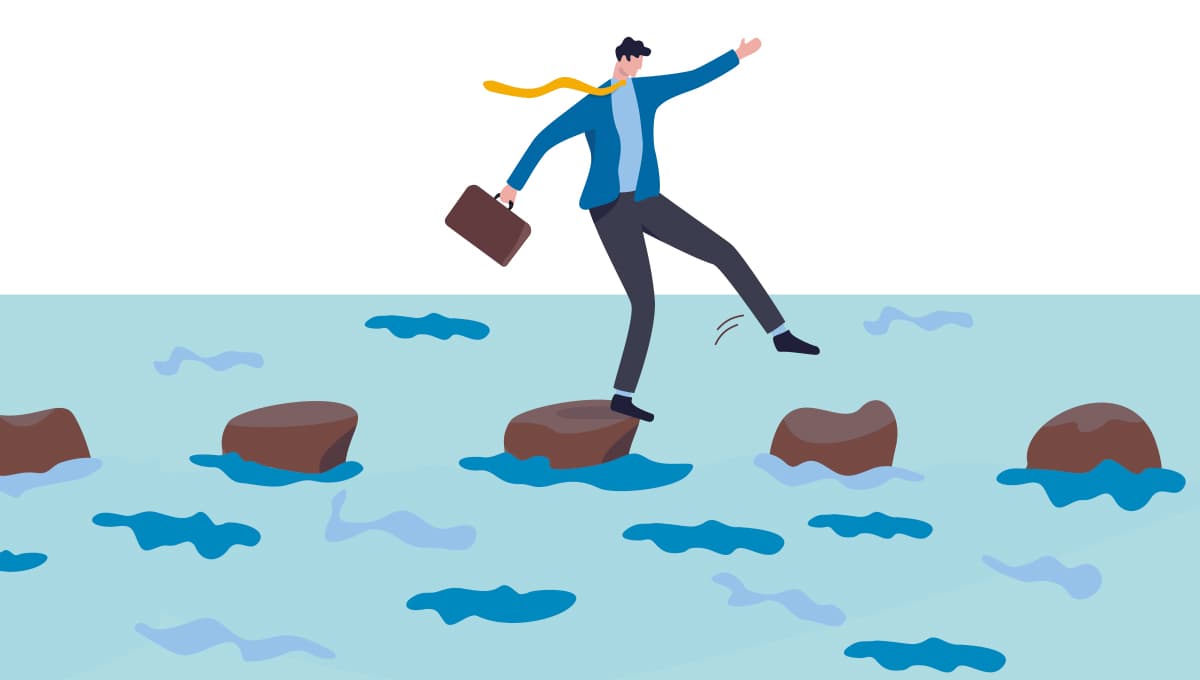 A businessman walks across stepping stones on water