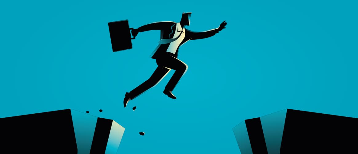 A businessman jumps from a crumbling cliff onto a safe cliff