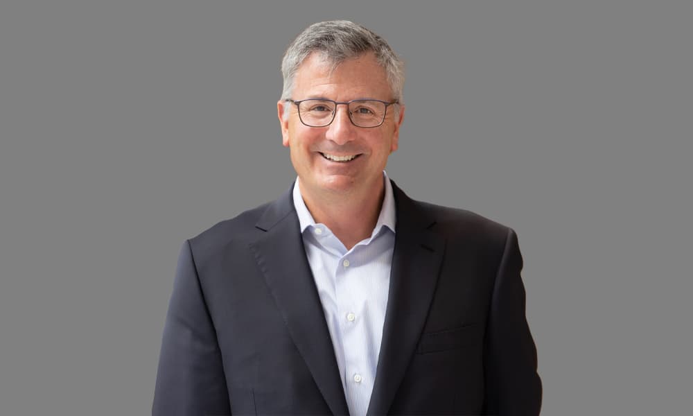 Headshot of Erik Hirsch, co-CEO of Hamilton Lane, in a dark jacket and light shirt against a gray background.